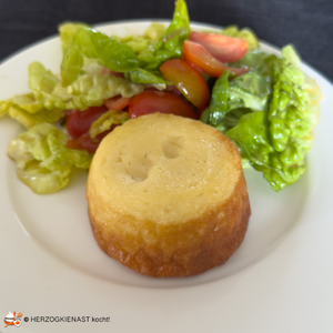 Parmesan Lavatörtchen mit Tomaten-Römersalat auf weißem Teller noch nicht aufgeschnitten