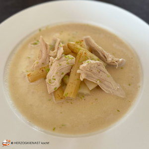 Poached chicken breast with white asparagus and chocolate on a white plate