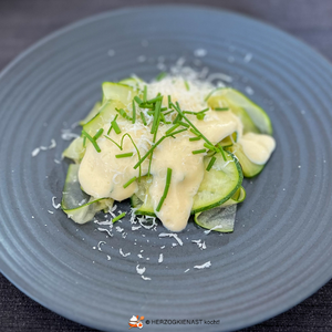 Zuccini carpaccio raw marinated - with parmesan zabaglione, sreved on a black plate