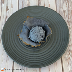 Schwarzes Kokoseis in schwarzer Waffelschale auf grauem Teller