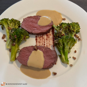 Venison with broccoli, pecan and olive cream served on a plate