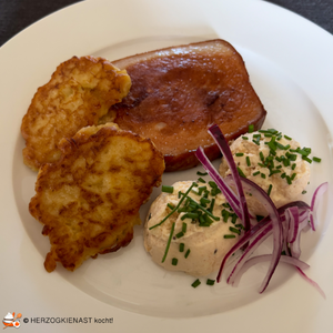 Sauerkrautpuffer mit Leberkäs und Obazda garniert mit roten Zwiebeln