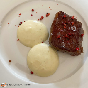 Steaks mit Polentaespuma und roten Beeren auf weißem Teller