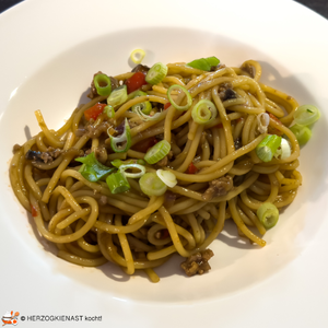 Koreanische Hackfleischpasta in tiefem Teller serviert mit Frühlingszwiebelringen