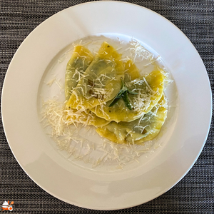 Ravioli mit Ricottta-Spinatfüllung und Salbeibutter, mit Parmesan auf weißem Teller
