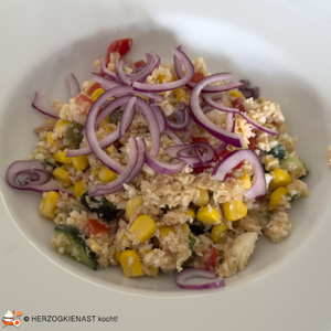 Bunter Salat mit Blumenkohl auf weißem Teller, getoppt mit roten Zwiebeln